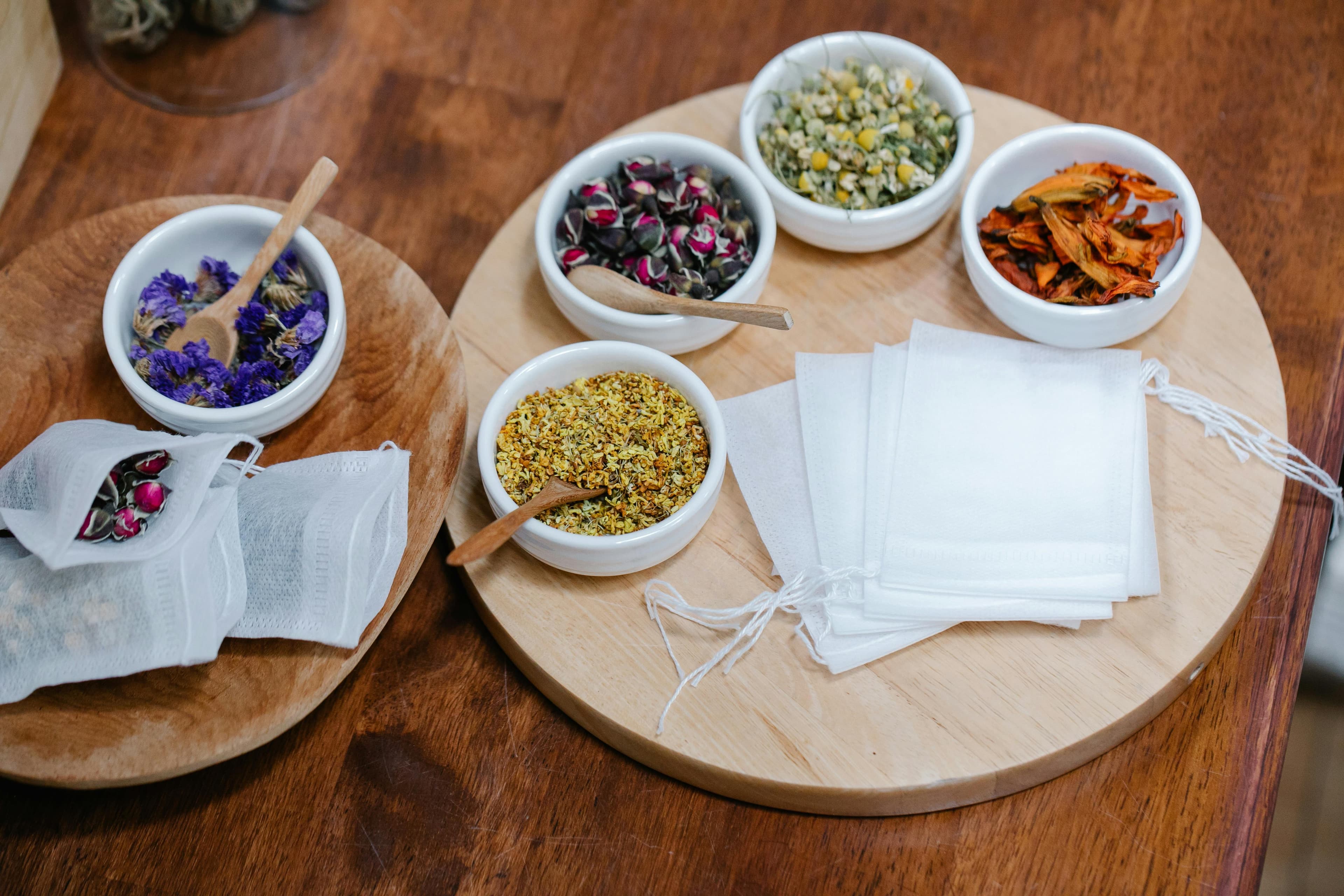 Herbal tea preparations with dried flowers and leaves in wooden bowls